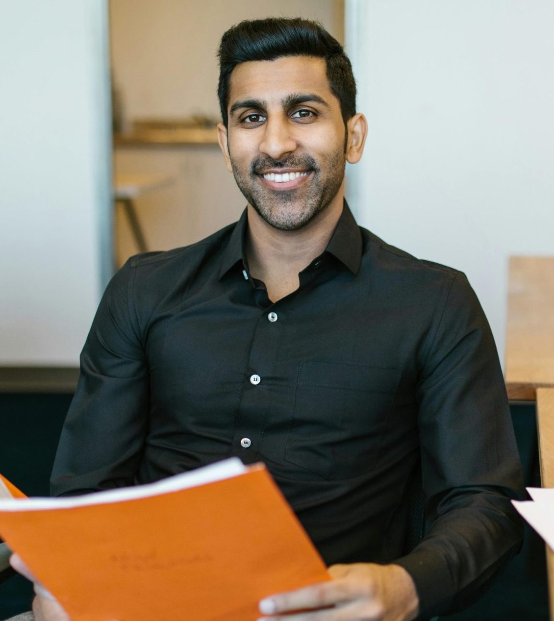 Smiling businessman holding documents at his desk, embracing productivity in a modern office.